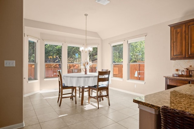 dining area with an inviting chandelier, light tile patterned floors, and vaulted ceiling