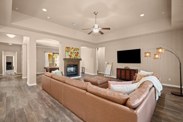 living room with hardwood / wood-style floors, a raised ceiling, and ceiling fan