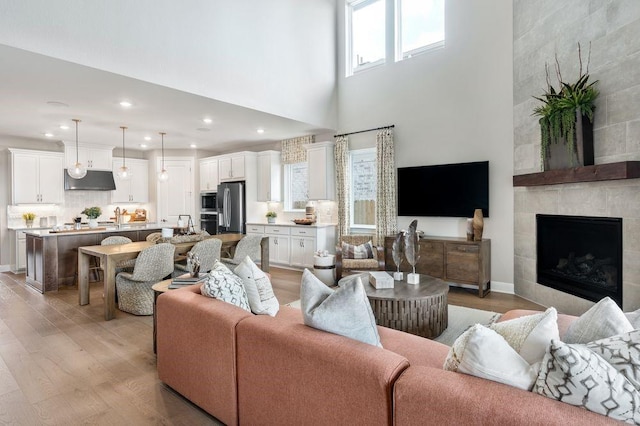 living room featuring a fireplace, light hardwood / wood-style flooring, and a towering ceiling