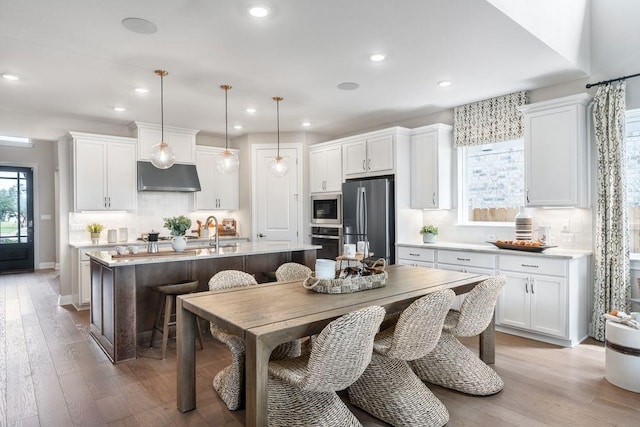 kitchen featuring white cabinetry, an island with sink, pendant lighting, and appliances with stainless steel finishes