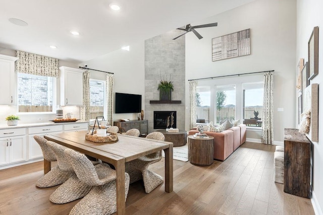 dining area featuring ceiling fan, light hardwood / wood-style floors, and a fireplace