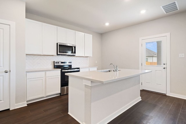 245 Little Green Trl, Jarrell, TX 76537 - kitchen with appliances with stainless steel finishes, dark wood-style flooring, an island with sink, backsplash, and light countertops