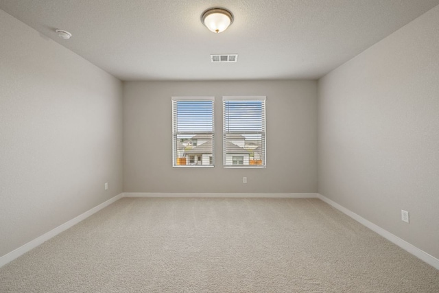 empty room with a smoke detector, light colored carpet, and baseboards