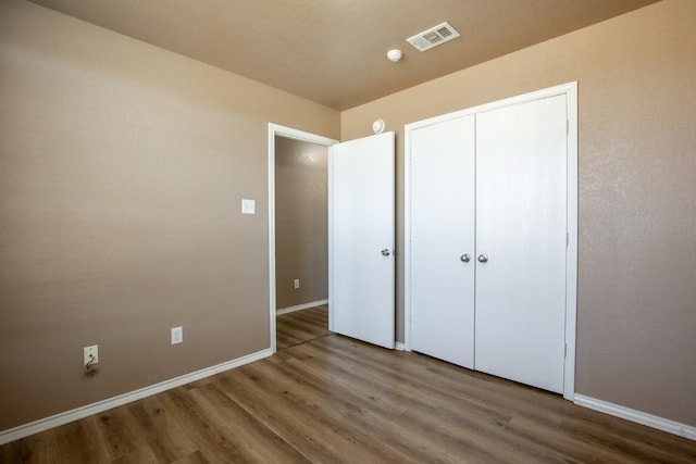 unfurnished bedroom with wood-type flooring and a closet