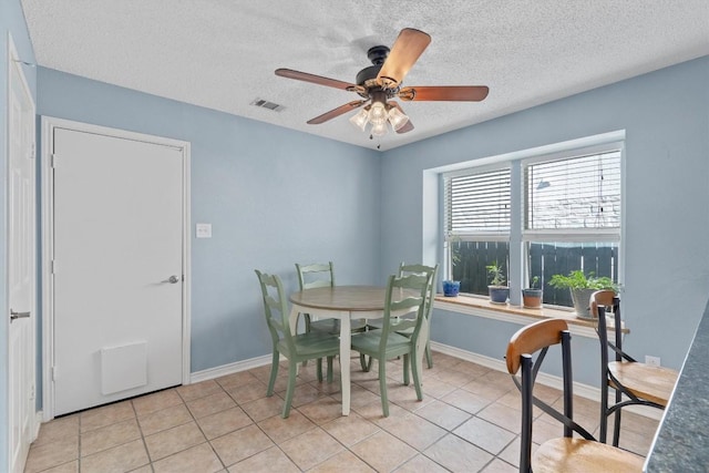 dining area with a textured ceiling, ceiling fan, and light tile patterned flooring