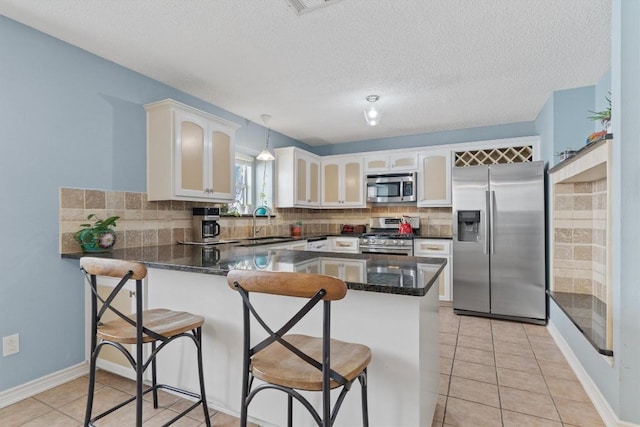 kitchen featuring pendant lighting, a breakfast bar, kitchen peninsula, stainless steel appliances, and white cabinets