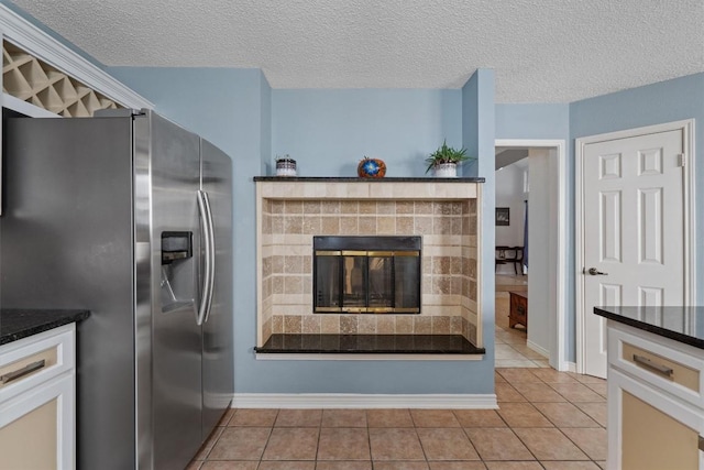 kitchen featuring light tile patterned floors, a textured ceiling, and stainless steel refrigerator with ice dispenser