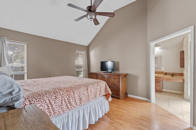 bedroom with ceiling fan, connected bathroom, high vaulted ceiling, and light wood-type flooring