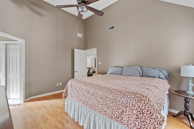 bedroom with ceiling fan, light hardwood / wood-style floors, and a towering ceiling