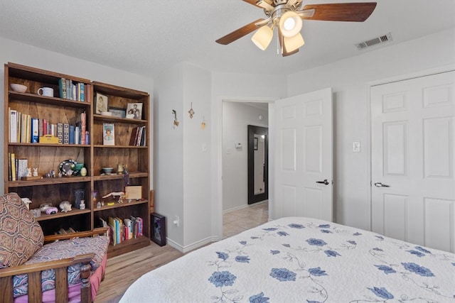 bedroom with light wood-type flooring, ceiling fan, and a textured ceiling