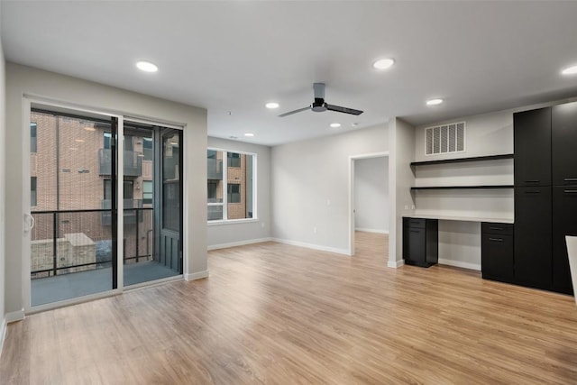 unfurnished living room featuring ceiling fan, light hardwood / wood-style floors, and built in desk