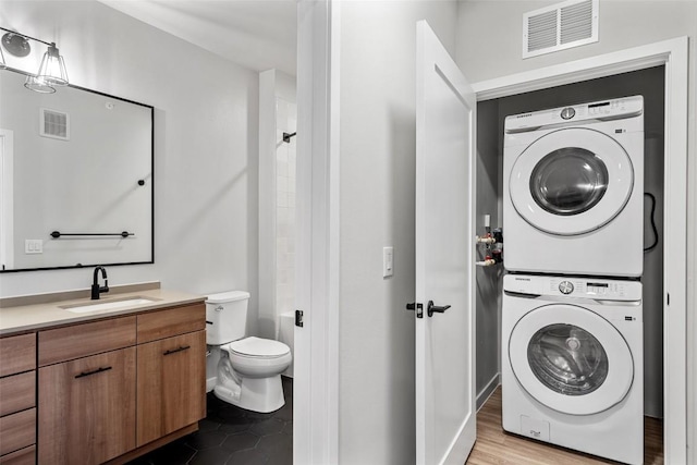 washroom featuring sink, stacked washer and clothes dryer, and light wood-type flooring