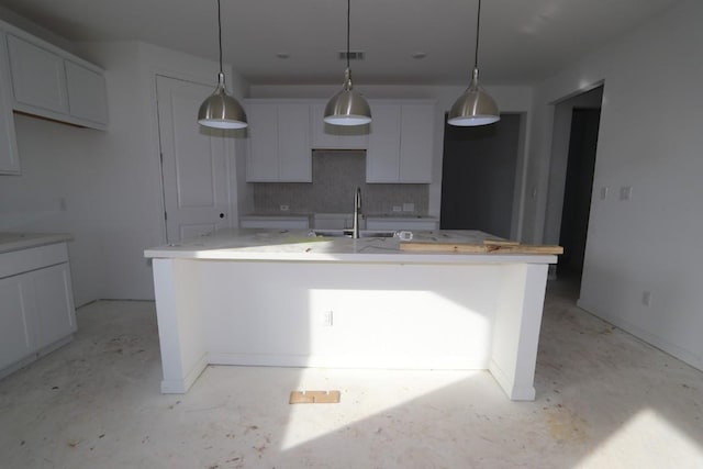 kitchen with white cabinets, pendant lighting, sink, and an island with sink