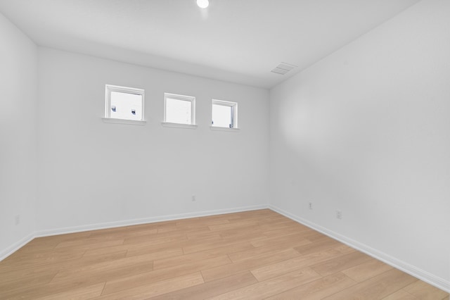 spare room with light wood-style flooring, visible vents, and baseboards