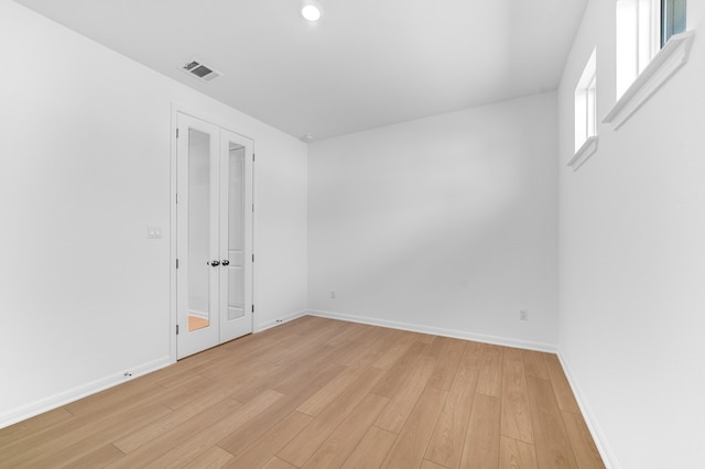 unfurnished room featuring light wood finished floors, visible vents, and baseboards