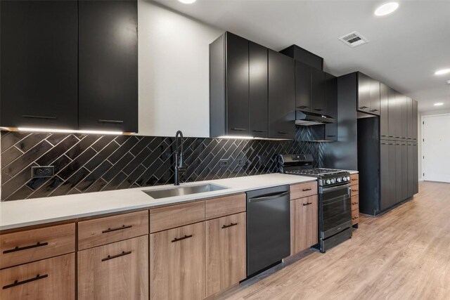 kitchen featuring stainless steel gas stove, dishwasher, sink, light hardwood / wood-style floors, and decorative backsplash