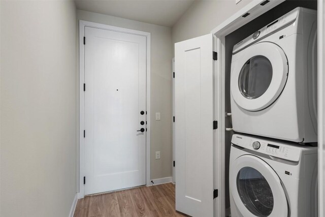 washroom featuring stacked washer and clothes dryer and light wood-type flooring