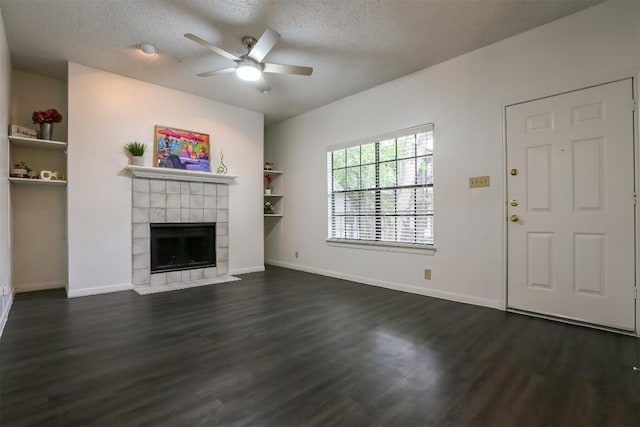 unfurnished living room featuring dark hardwood / wood-style floors, ceiling fan, a textured ceiling, and a tiled fireplace