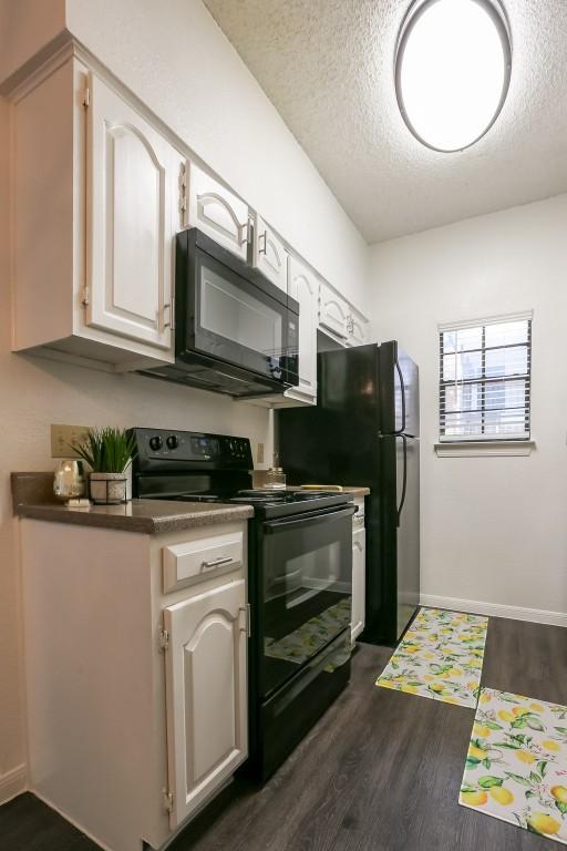 kitchen featuring black appliances, dark hardwood / wood-style flooring, white cabinets, and a textured ceiling