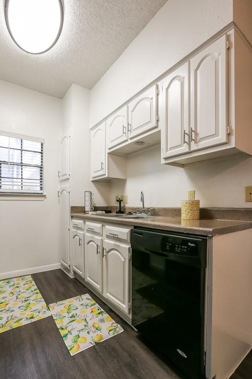 kitchen featuring white cabinetry, sink, dark wood-type flooring, black dishwasher, and a textured ceiling