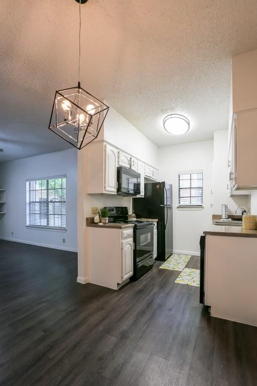 kitchen with pendant lighting, black appliances, dark hardwood / wood-style floors, a textured ceiling, and white cabinetry