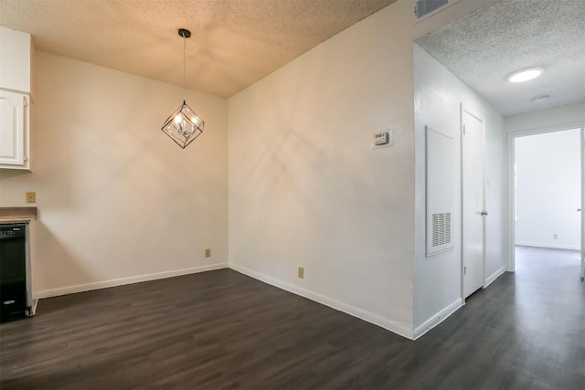 unfurnished dining area featuring dark hardwood / wood-style flooring, a textured ceiling, and a notable chandelier