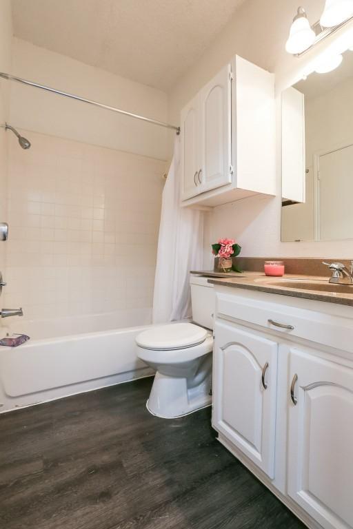 full bathroom featuring shower / bath combo, vanity, hardwood / wood-style flooring, and toilet