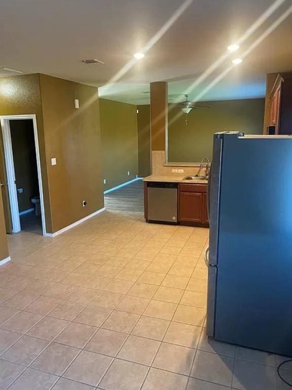 kitchen with ceiling fan, sink, stainless steel dishwasher, black refrigerator, and light tile patterned floors