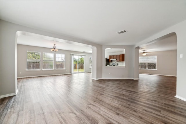 unfurnished living room with dark hardwood / wood-style flooring and ceiling fan with notable chandelier