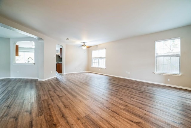 unfurnished room with ceiling fan, a healthy amount of sunlight, and dark hardwood / wood-style floors