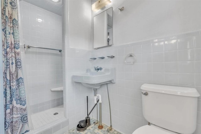 bathroom with tile patterned floors, toilet, tile walls, and walk in shower