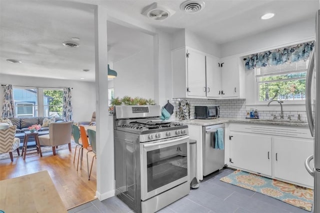 kitchen with white cabinets, plenty of natural light, sink, and stainless steel appliances