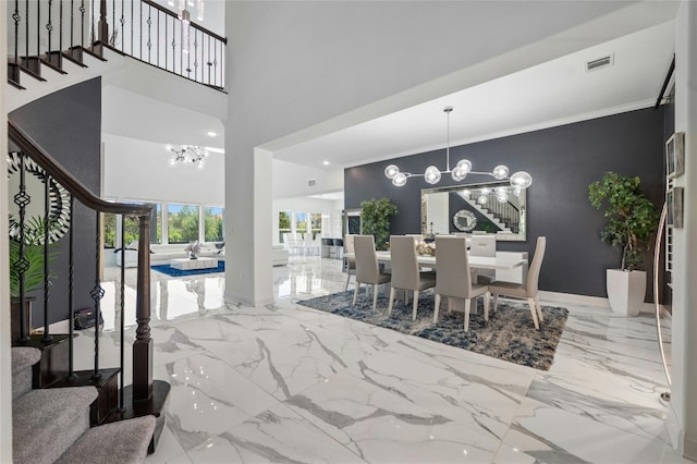 dining area featuring a notable chandelier, a towering ceiling, and crown molding