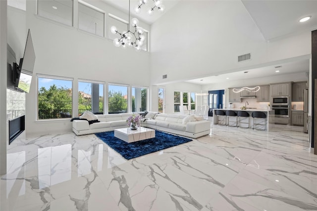 living room featuring a fireplace, plenty of natural light, a towering ceiling, and an inviting chandelier