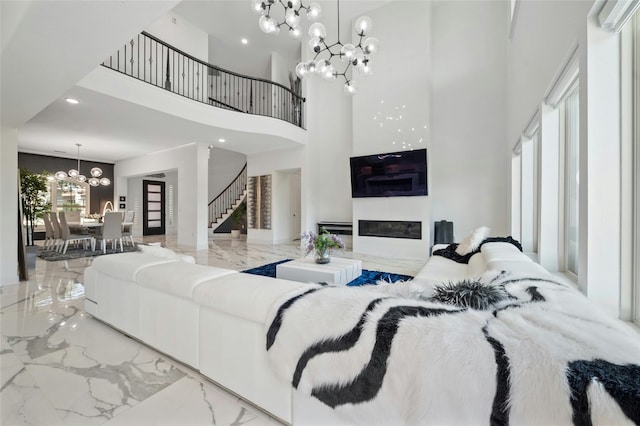 living room featuring plenty of natural light, a towering ceiling, and a notable chandelier