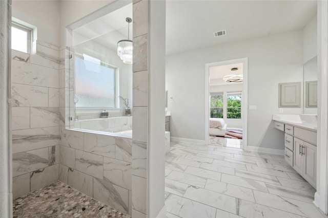 bathroom with tiled shower, vanity, and a chandelier