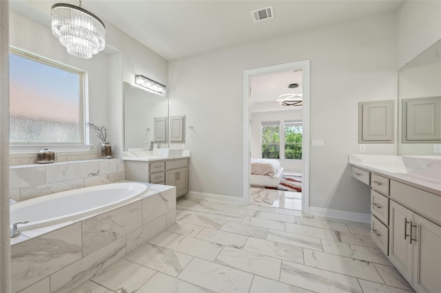 bathroom with a notable chandelier, vanity, and a relaxing tiled tub