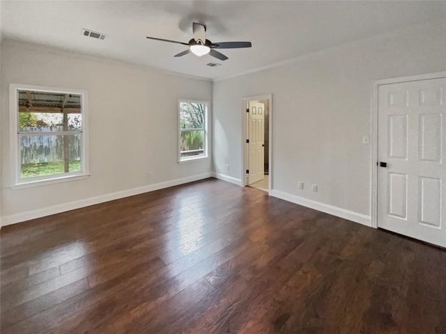 empty room with dark hardwood / wood-style flooring, plenty of natural light, ornamental molding, and ceiling fan