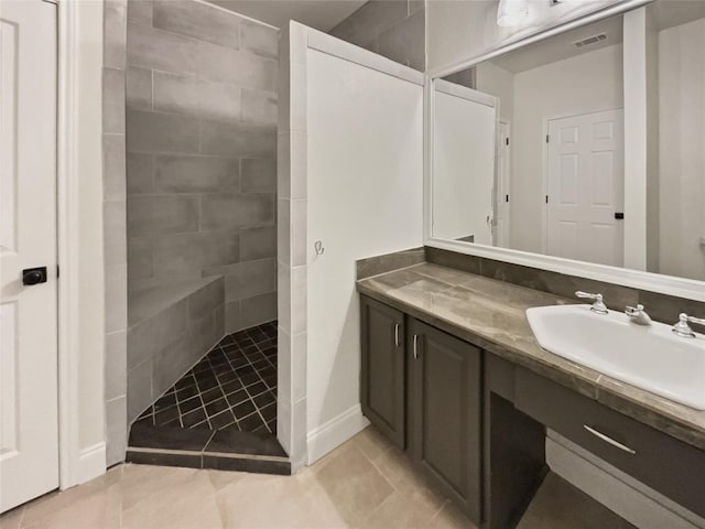 bathroom with a tile shower, vanity, and tile patterned floors