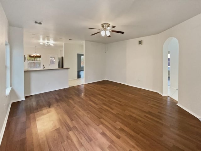 unfurnished living room featuring wood-type flooring and ceiling fan with notable chandelier