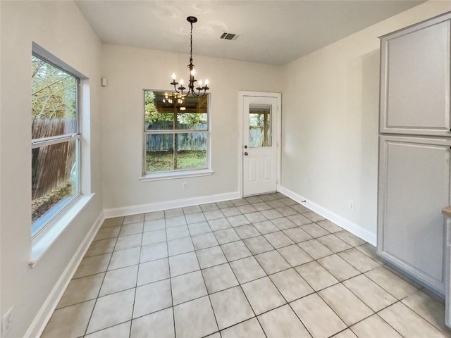 unfurnished dining area with a chandelier, a healthy amount of sunlight, and light tile patterned flooring