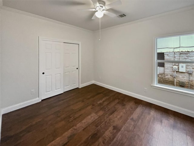 unfurnished bedroom featuring ceiling fan, dark hardwood / wood-style flooring, crown molding, and a closet