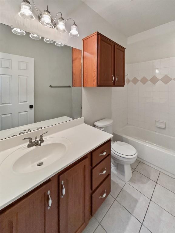 full bathroom with tiled shower / bath, tile patterned flooring, vanity, and toilet