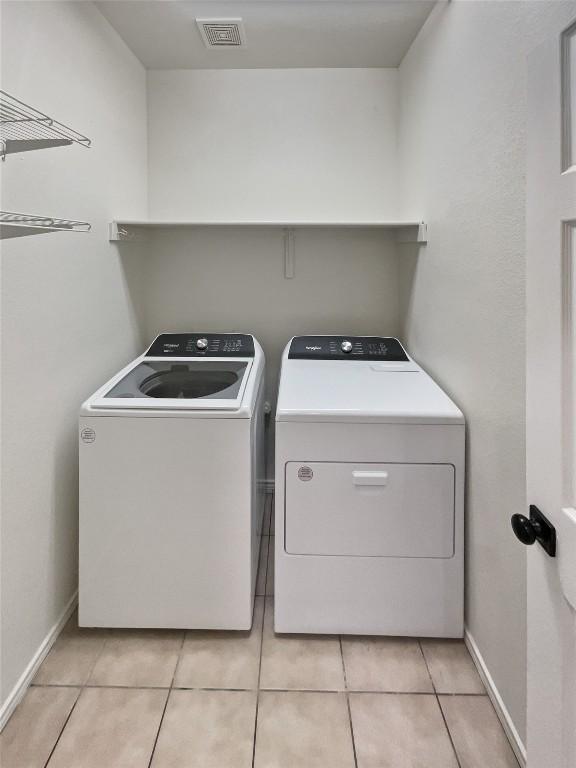 washroom featuring washing machine and dryer and light tile patterned floors