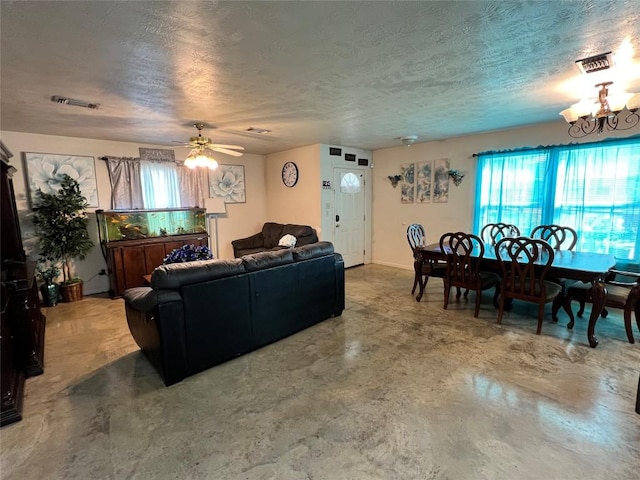 living room featuring ceiling fan with notable chandelier, concrete floors, and a textured ceiling