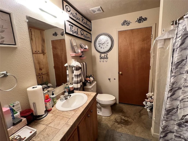 bathroom with vanity, a textured ceiling, and toilet