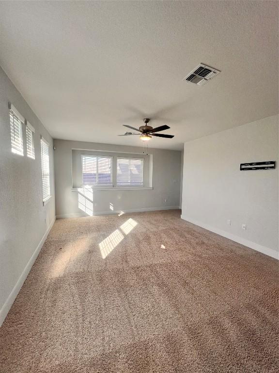 spare room with carpet flooring, ceiling fan, and a textured ceiling