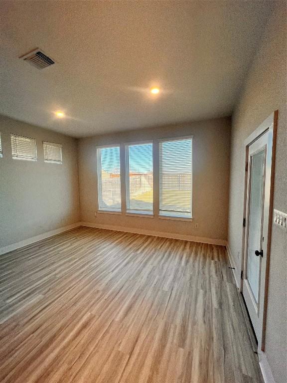 spare room with a textured ceiling and light wood-type flooring