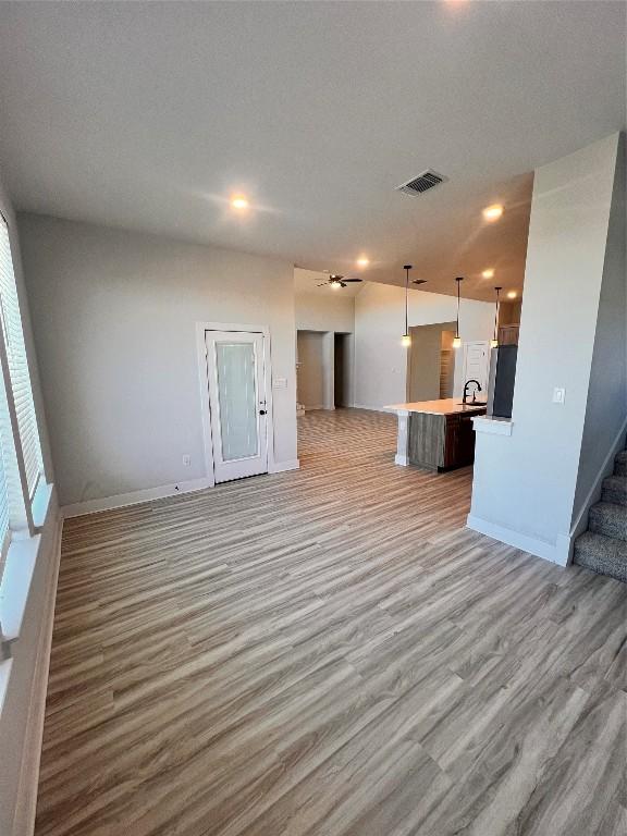 unfurnished living room with sink, a textured ceiling, and light wood-type flooring