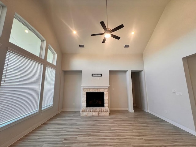 unfurnished living room featuring ceiling fan, a fireplace, high vaulted ceiling, and light hardwood / wood-style flooring